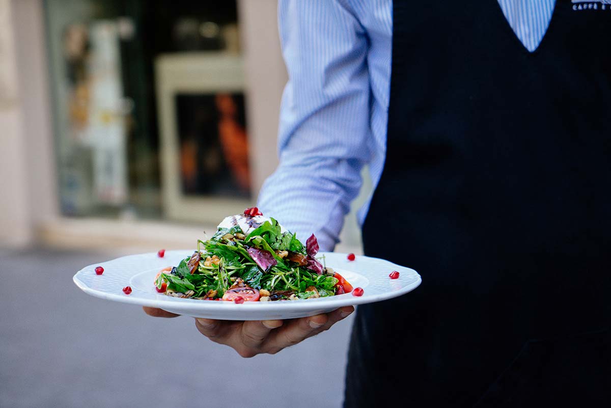 A server carrying a plate of salad